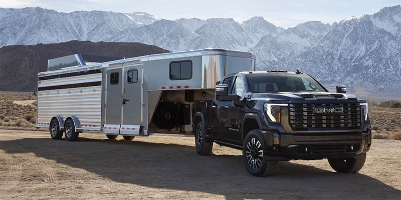 A black 2024 GMC Sierra 3500 HD parked with a trailer hitched to the back
