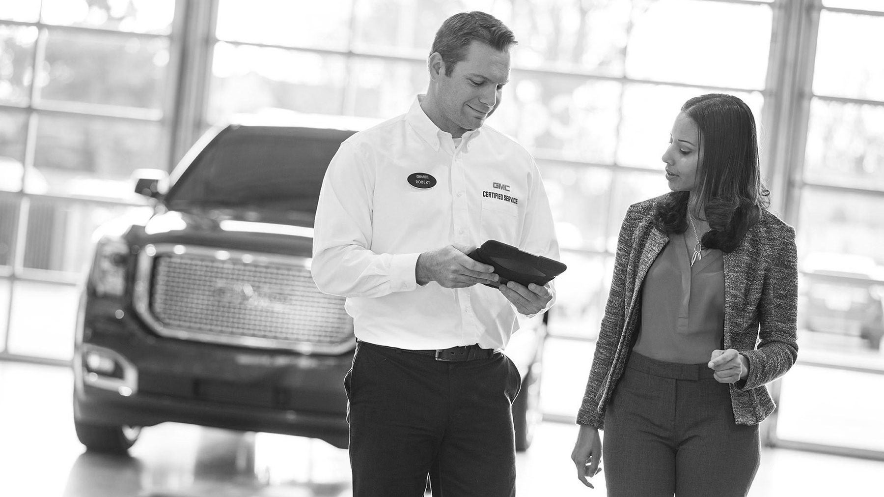 GMC employee discussing finance options with customer at the GMC dealership with a GMC model visible in the background