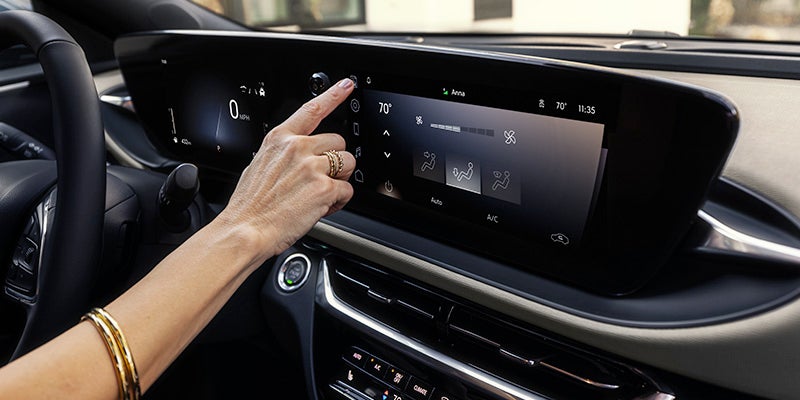 View of a woman's hand touching the screen of the Buick infotainment system