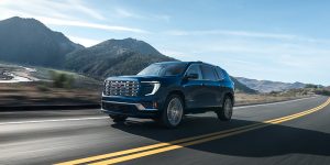 The 2025 GMC Acadia driving down a highway with a nice scenic view.