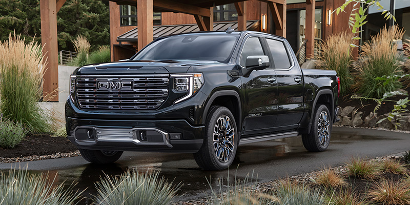 A black GMC Sierra 1500 pickup truck parked outside a modern building.